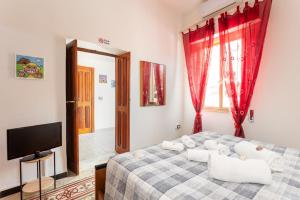 a bedroom with a bed with red curtains and a tv at La Campidanese IUN R3640 in Càbras
