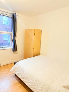 a bedroom with a bed and a window at Spacious Room with Double and semi double bed, Shared bathroom,10 minutes to Aldgate East station, near Central London, for 4 ppl in London