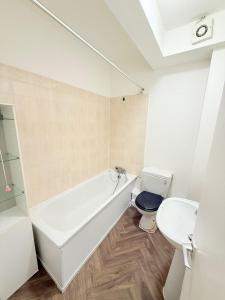 a bathroom with a white tub and a toilet at Spacious Room with Double and semi double bed, Shared bathroom,10 minutes to Aldgate East station, near Central London, for 4 ppl in London