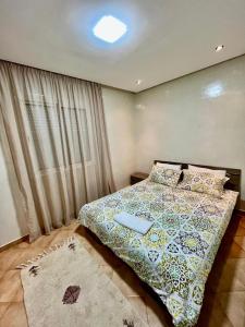 una camera da letto con un letto con un piumone e una finestra di Harhoura, plage, piscine et confortable a El Harhoura