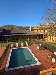 a swimming pool with chairs and tables and a house at Pousada Maritaca in Bonito