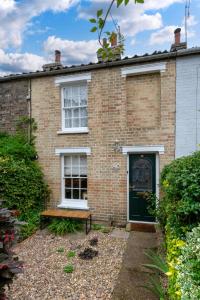 a brick house with a green door and a bench at Scribblers Cottage in Woodbridge