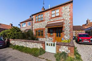 a red car parked in front of a brick house at 1 Street Farm Cottages in Bodham