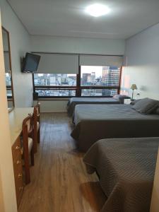 a hotel room with three beds and a flat screen tv at Tango BA in Buenos Aires