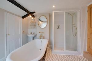 a white bath tub in a bathroom with a shower at Bizewell Farmhouse in Trimingham