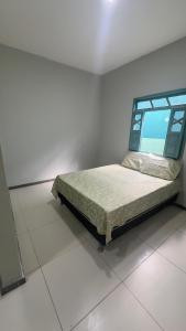 a bed in a white room with a window at Casa 650m da Orla da Atalaia in Aracaju