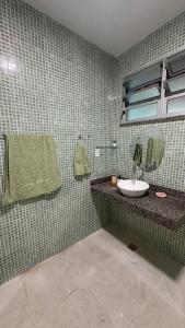a green tiled bathroom with a sink and a mirror at Casa 650m da Orla da Atalaia in Aracaju