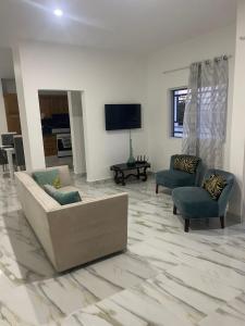 a living room with a couch and two chairs and a tv at res Montesino in San Felipe de Puerto Plata