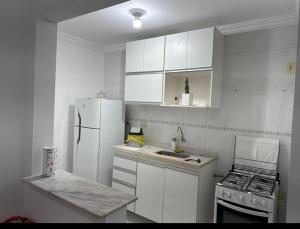 a kitchen with white cabinets and a white refrigerator at Apto mobiliado no edificio saveiro com garagem in São José dos Campos
