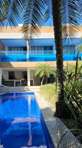 a building with a swimming pool next to a palm tree at Pousada Exclusive in Florianópolis +18 photos