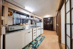 a kitchen with white cabinets and a refrigerator at Former Yoshidaya Hikonana Residence, a Registered Tangible Cultural Property 倉敷の宿 国登録有形文化財 旧吉田彦七邸 一棟貸切 1日1組限定 特別な体験 日本の伝統建築で過ごす非日常を in Kurashiki