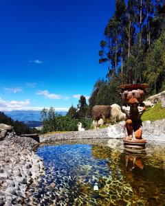 a fire hydrant next to a pond with animals in the background at Hacienda Rumiloma by Rotamundos in Quito