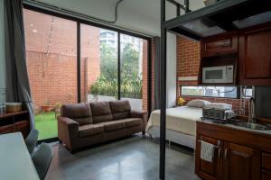 a bedroom with a bed and a couch and a window at Cómodo loft en centro de zona 4 in Guatemala