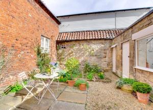 a patio with a table and chairs in front of a brick building at Mundles Cottage in Whittingham