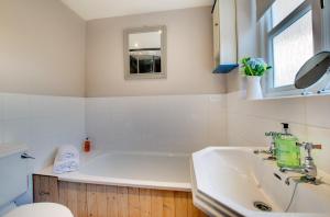 a white bathroom with a tub and a sink at Mundles Cottage in Whittingham