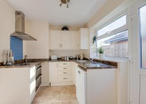 Una cocina con gabinetes blancos y una ventana. en Oaklea, en Burnham Market
