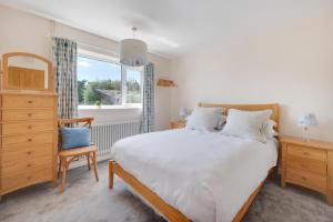 Un dormitorio con una gran cama blanca y una ventana. en Oaklea, en Burnham Market