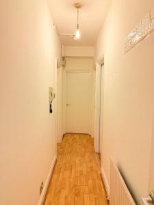 a hallway with a white door and a wooden floor at The settle Nest- Bright Semi Double room for 2ppl with shared bathroom-10 minutes to Aldgate East Station, close to central London, in London