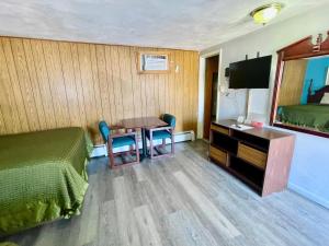 Una habitación de hotel con una cama, un escritorio y una mesa. en Travelers Inn Olney, en Olney