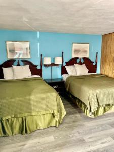 Dos camas en una habitación con paredes azules. en Travelers Inn Olney, en Olney