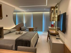 a hotel room with a bed and a desk and a kitchen at Studio beira mar próximo do centro de convenções em Armação in Salvador