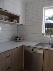 a kitchen with a sink and a dishwasher at Beach Cottage in Mount Maunganui +5 photos