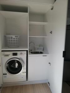 a laundry room with a washing machine and a sink at Beach Cottage in Mount Maunganui