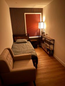 a bedroom with a bed and a chair and a lamp at Modern East London Apartment with Private Studio & Guest Rooms-Near Bow, Victoria Park in London