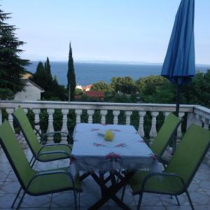 a table and chairs on a balcony with an umbrella at Apartments Kristic in Lovran