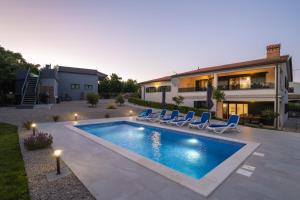 a swimming pool with chairs and a house at Luxury villa with a swimming pool Trget, Rasa - 23420 in Trget