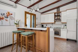 a kitchen with white cabinets and bar stools at Luxury villa with a swimming pool Trget, Rasa - 23420 in Trget