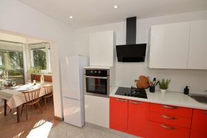 a kitchen with red cabinets and a white refrigerator at Seaside house for families with children Banj, Pasman - 24665 in Kukljica