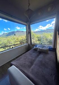 a bedroom with a large bed and large windows at Loft Urucum a 700 metros da vila-Vale do Capao in Palmeiras