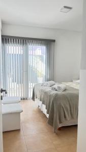 une chambre avec deux lits et une grande fenêtre dans l'établissement Los Soles de Madryn, à Puerto Madryn