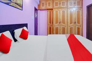 a bedroom with two beds with red pillows and a wooden door at Super Hotel O New View in Bankipur