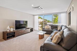 a living room with a couch and a flat screen tv at Bayscape - Modern Beachside Retreat with Ocean View in Dunsborough