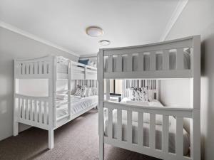 2 letti a castello bianchi in una camera di Bickley's Place - A Luxury Retreat on the Golf Green a Dunsborough
