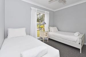 due letti in una stanza con finestra di Windella Cottage a North Rothbury