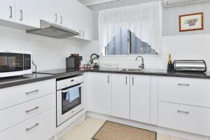 una cucina bianca con mobili bianchi e un forno a microonde di Windella Cottage a North Rothbury Altre 23 foto