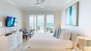 ein weißes Schlafzimmer mit Bett und Meerblick in der Unterkunft South Bay Beach Club #31- 3 Bedroom 2 Bathroom Unit in George Town