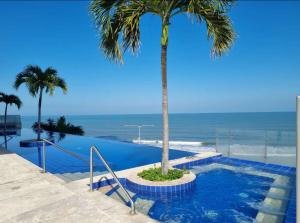 a palm tree in a pool with the ocean in the background at Ikigai frente al mar con piscina infinita y Gym in Cartagena de Indias