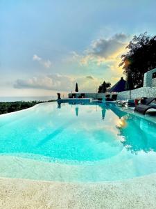 a large blue swimming pool with chairs and the ocean at Penida View Village - Infinity pool & Volcano View in Nusa Penida