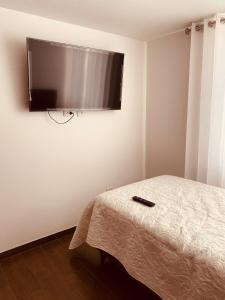 a flat screen tv on a wall with a bed at Departamento en estreno amoblado PERUMIN in Paucarpata