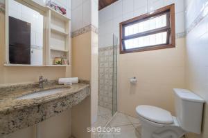 un bagno con un water, un lavandino e una finestra di Linda casa a 230m da praia de Bombas RGV115 a Bombas Altre 25 foto