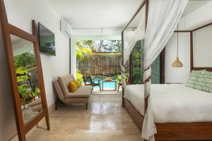 a bedroom with a bed and a chair and a table at Relaxing 2BR Condo Omara with Direct Pool Access in Tulum