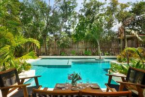 a pool with a table and chairs in front of it at Relaxing 2BR Condo Omara with Direct Pool Access in Tulum +13 photos