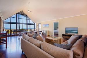 a living room with a large couch and a television at Bondys Beach House - Panoramic Beachside Living in Prevelly