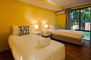 two beds in a room with yellow walls and a window at Bondys Beach House - Panoramic Beachside Living in Prevelly