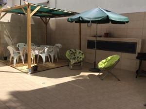 a patio with a table and chairs and an umbrella at Patacão&Violeta in Faro