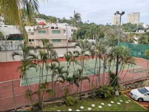 un court de tennis avec des palmiers dans une ville dans l'établissement Hermoso departamento en condominio de Costa Azul, à Acapulco